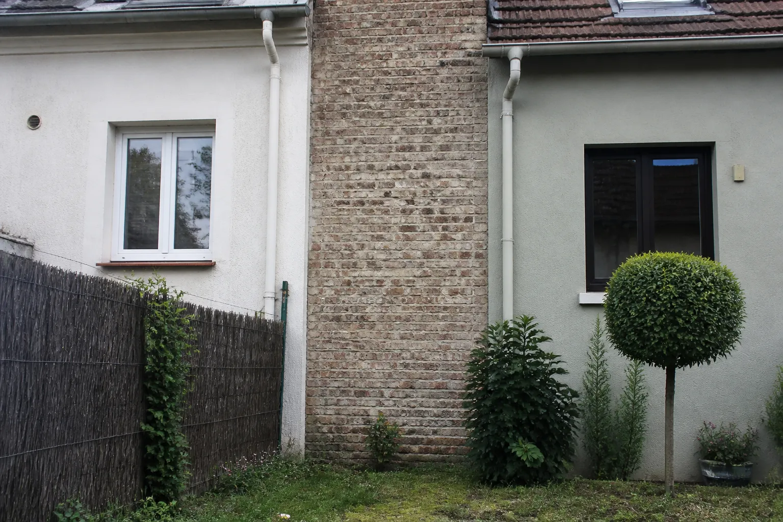 Mur mitoyen entre deux maisons vu depuis un jardin