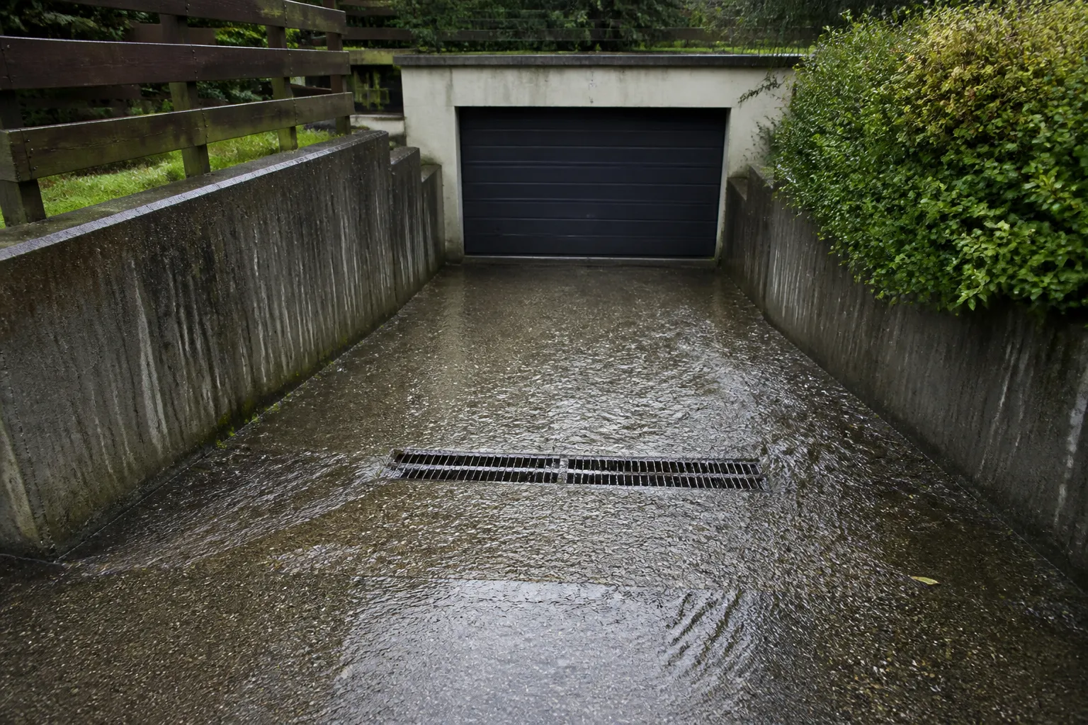 Eau de pluie ruisselant sur une allée vers une grille