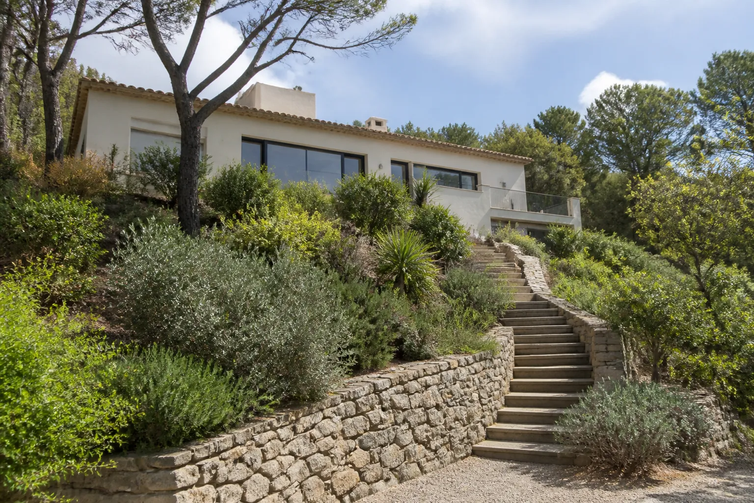 Terrain en pente avec mur de soutènement et maison au-dessus