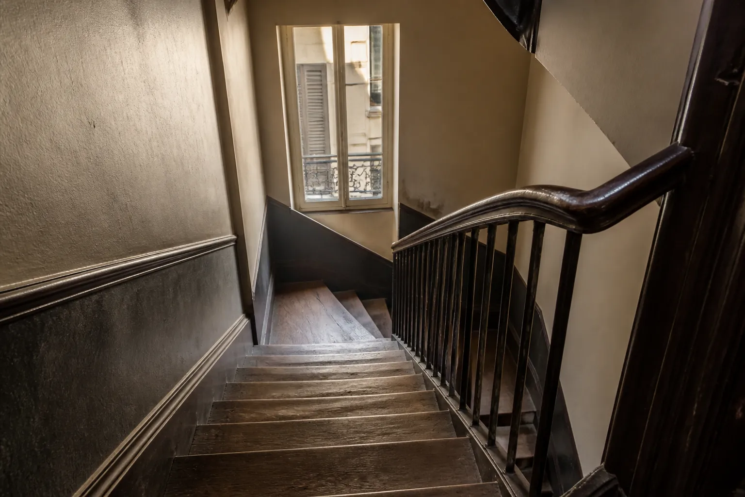 Cage d’escalier d’un immeuble ancien avec parquet et rampe en bois