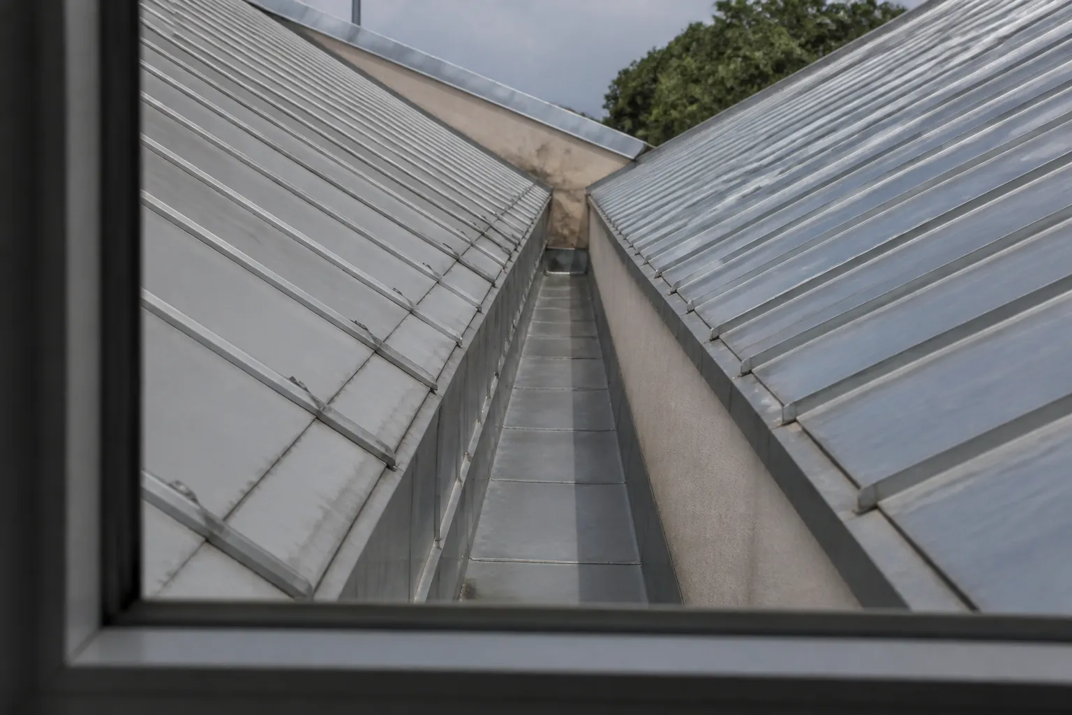 Chéneau entre deux pans de toiture vu depuis une fenêtre