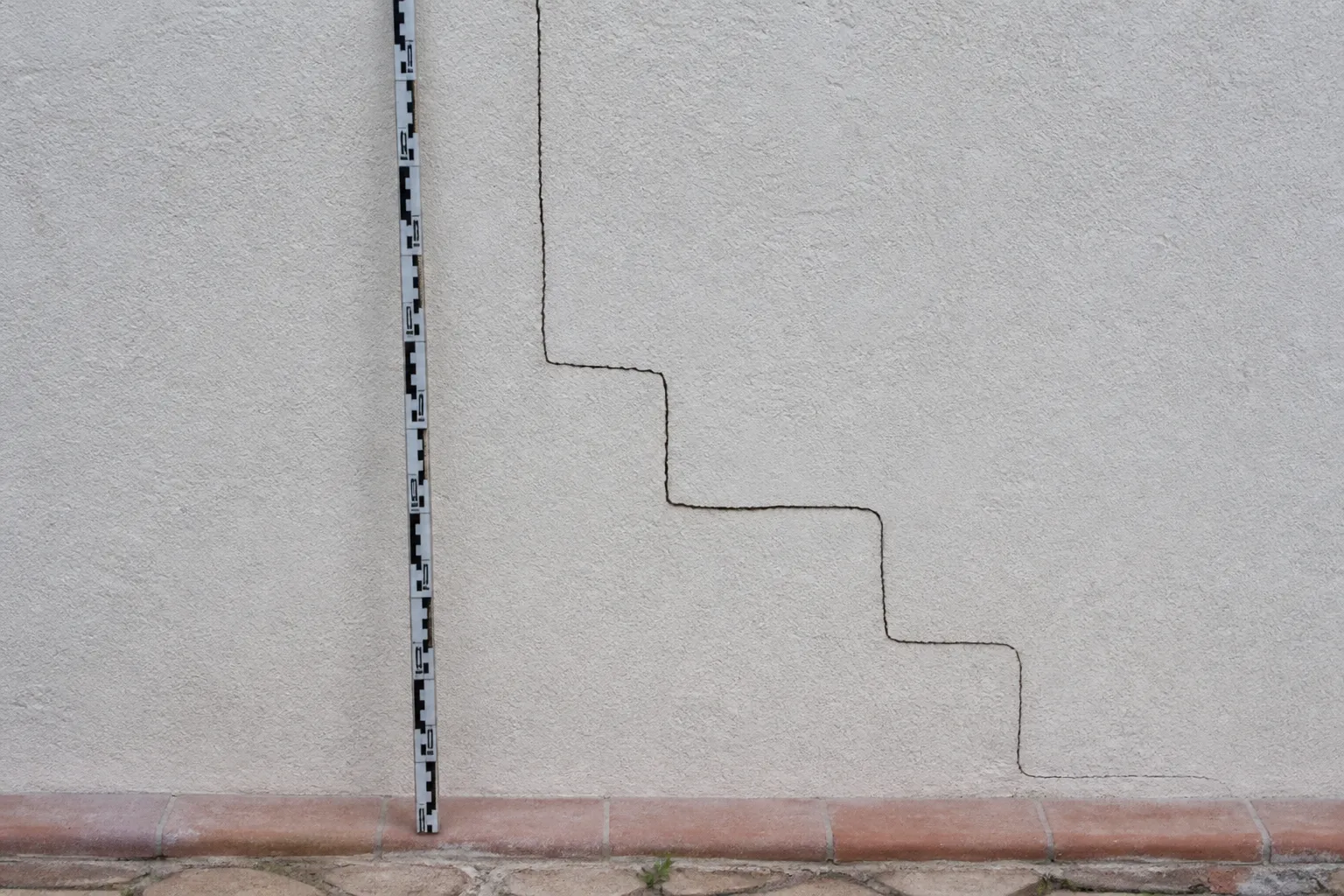 Fissure en escalier sur un mur de façade enduit
