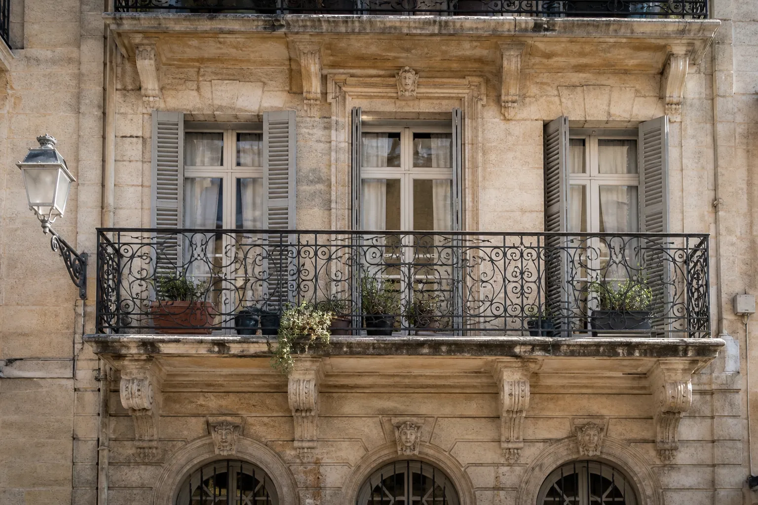 Façade d’immeuble ancien en pierre avec balcon en fer forgé