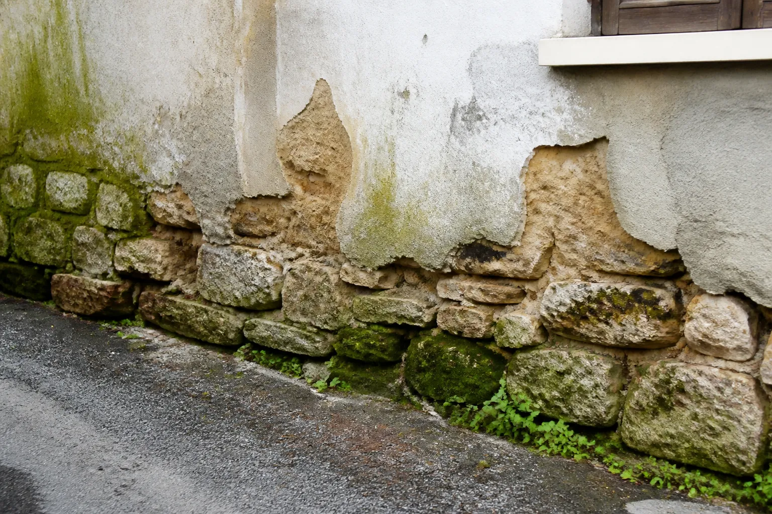 Pied de mur en pierre avec traces d’humidité au rez-de-chaussée
