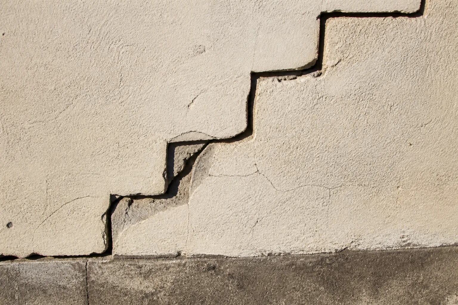 Fissure en escalier dans un mur de maçonnerie enduit