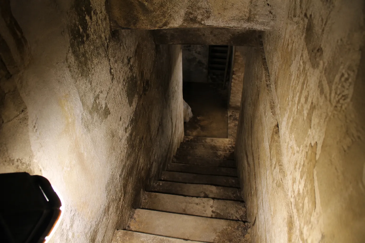 Escalier de cave en pierre éclairé par une lampe