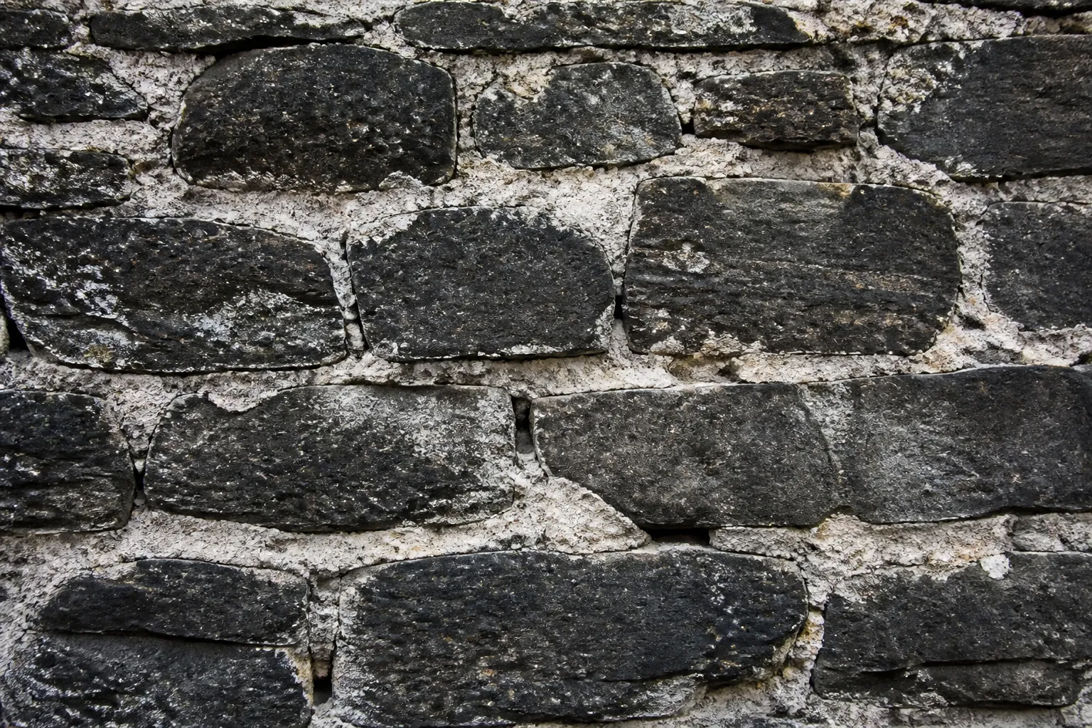 Mur ancien en pierre sombre avec joints à la chaux