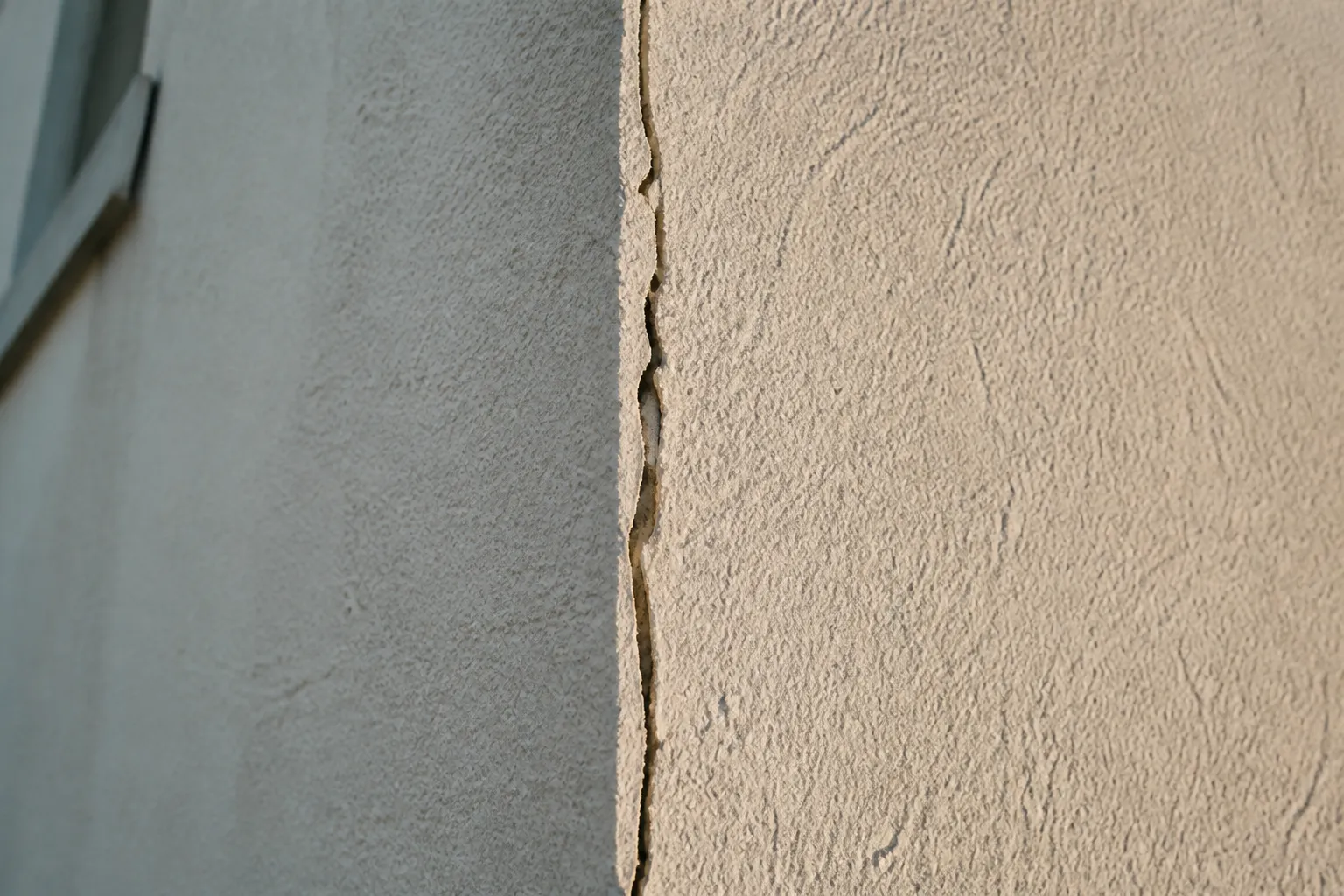 Fissure verticale à l’angle d’une maison enduite