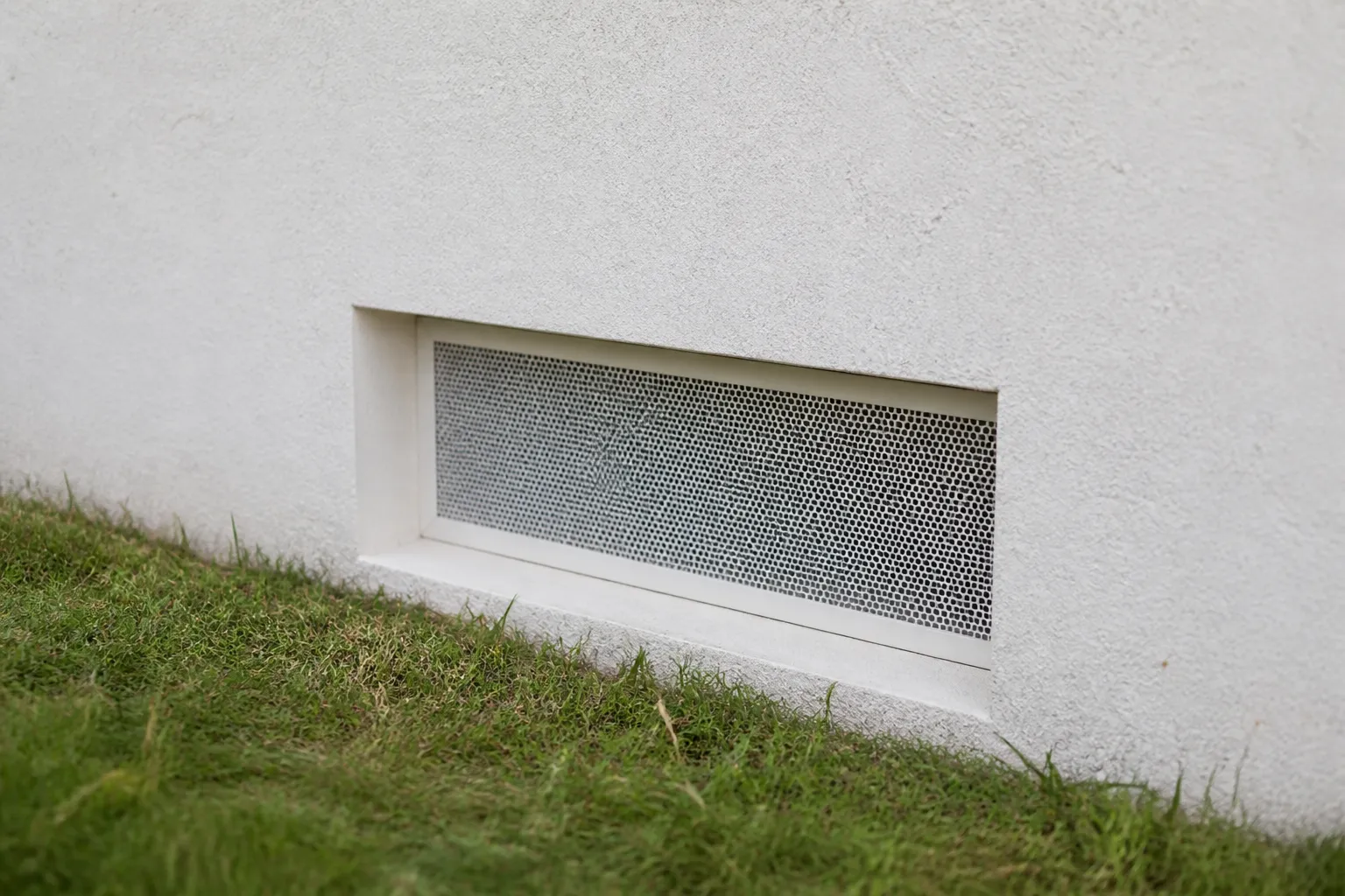 Grille de ventilation basse sur la façade d’une maison
