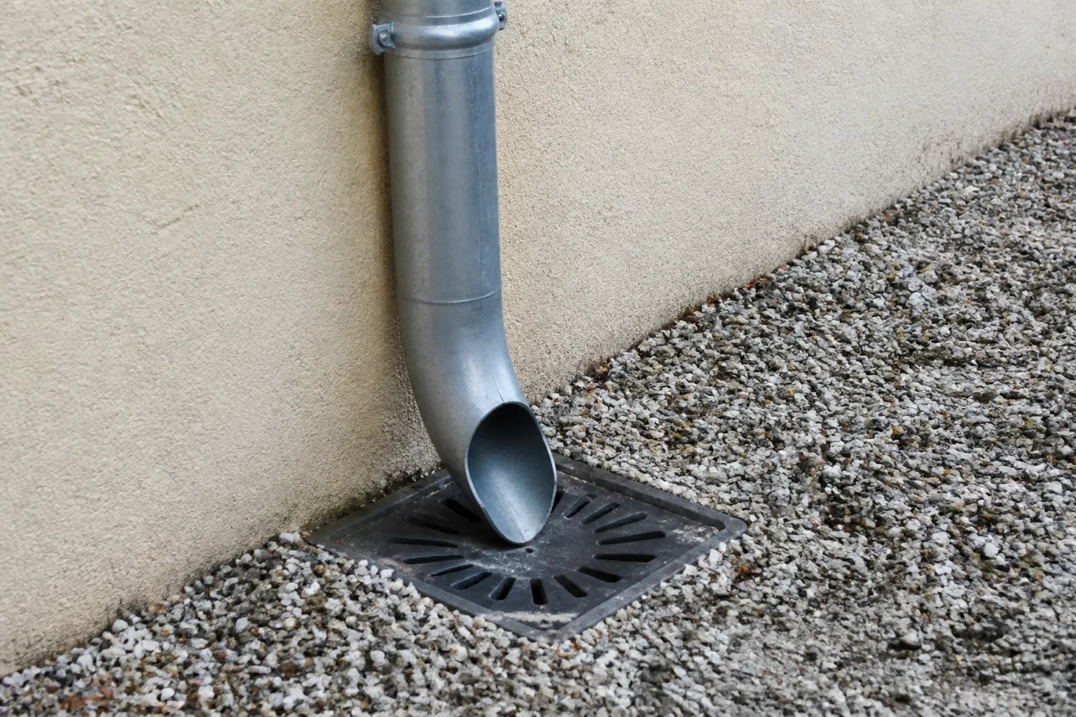 Descente de gouttière et regard d’eaux pluviales au pied d’une maison