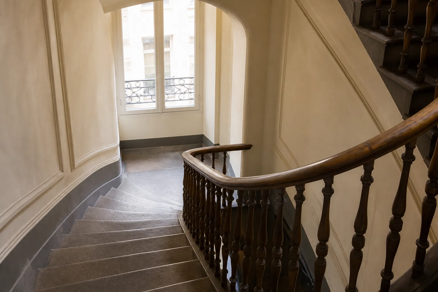 Cage d’escalier d’un immeuble ancien avec rampe en bois