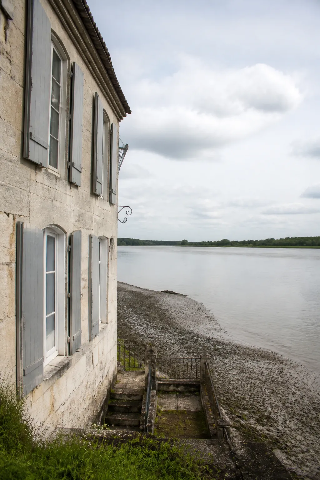 Maison ancienne en pierre claire au bord d’un fleuve estuarien