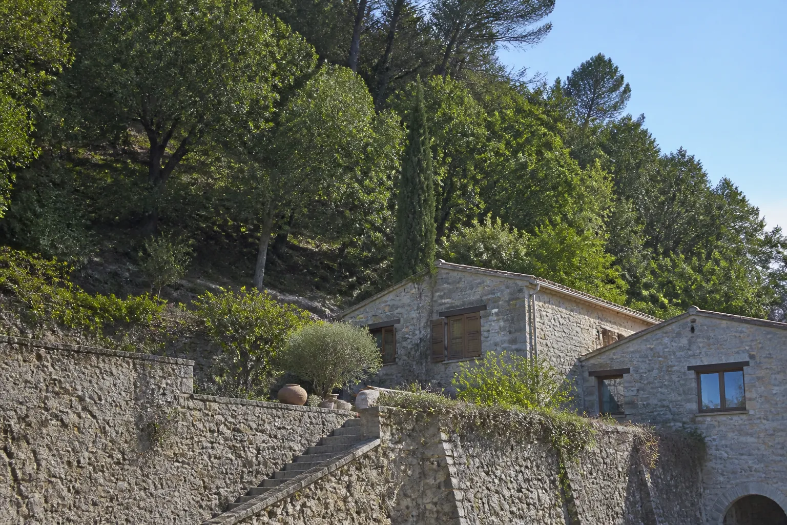 Pente boisée au-dessus de maisons avec un mur de pierre