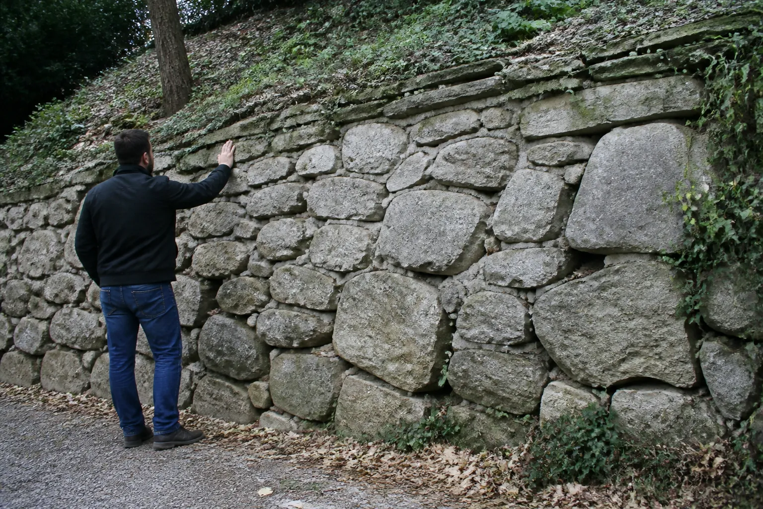Expert observant un mur de soutènement en pierre