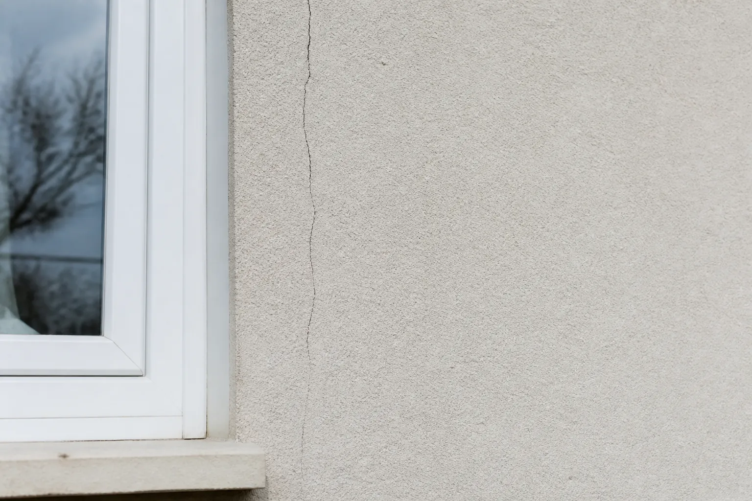 Fissure verticale sur une façade enduite