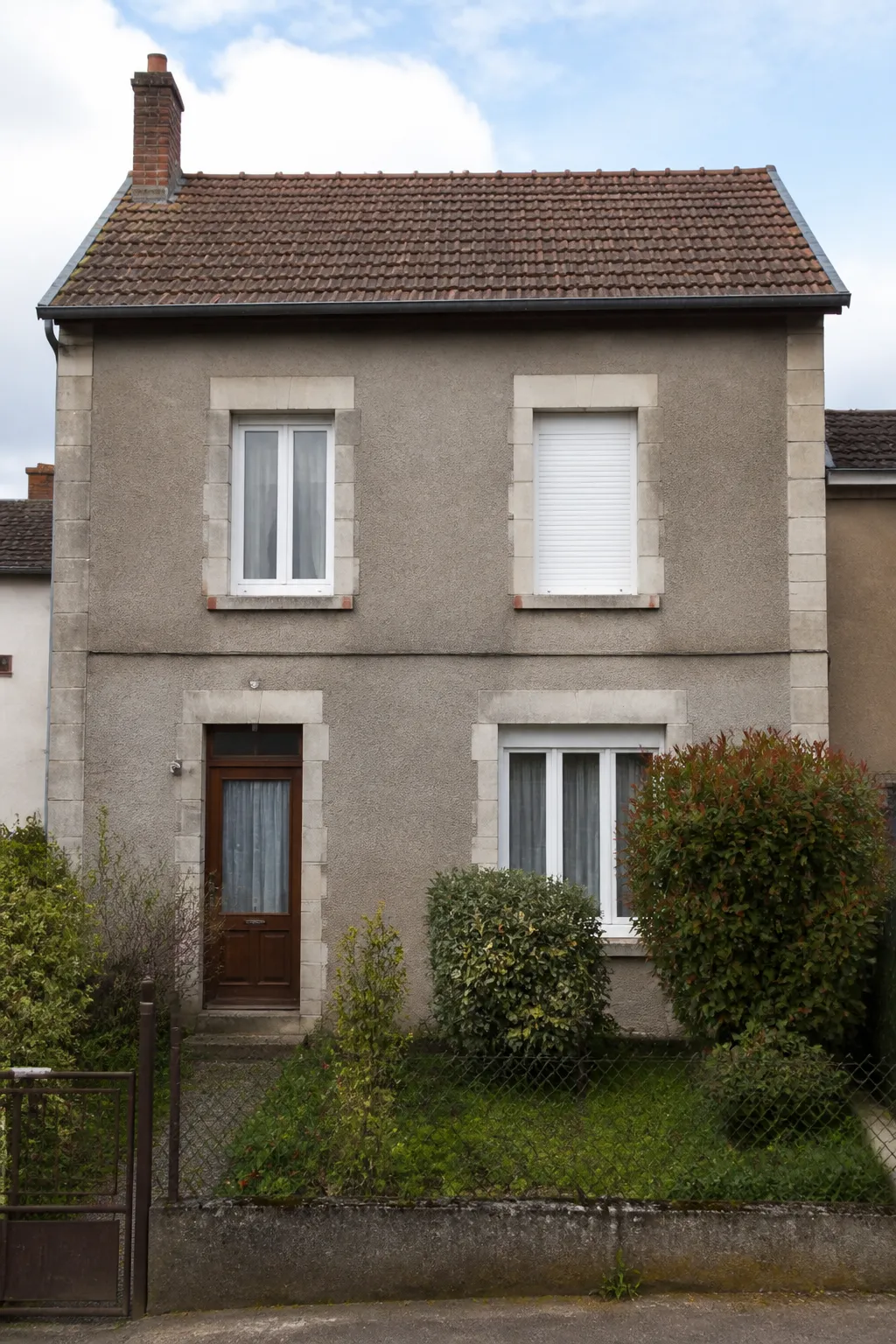 Maison ouvrière ancienne enduite avec toit de tuiles mécaniques dans une rue résidentielle