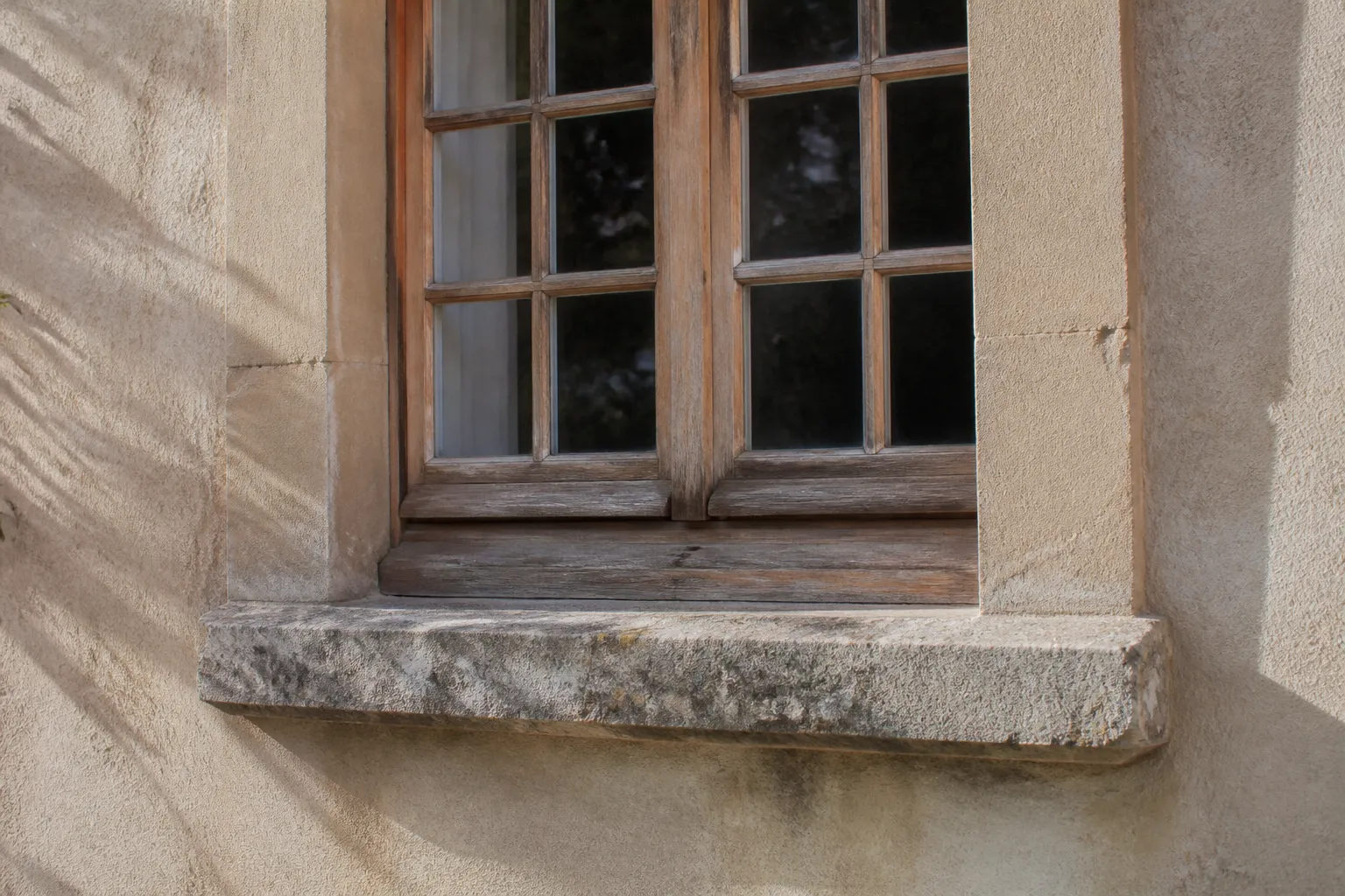 Fenêtre ancienne en bois avec appui en pierre sur une façade