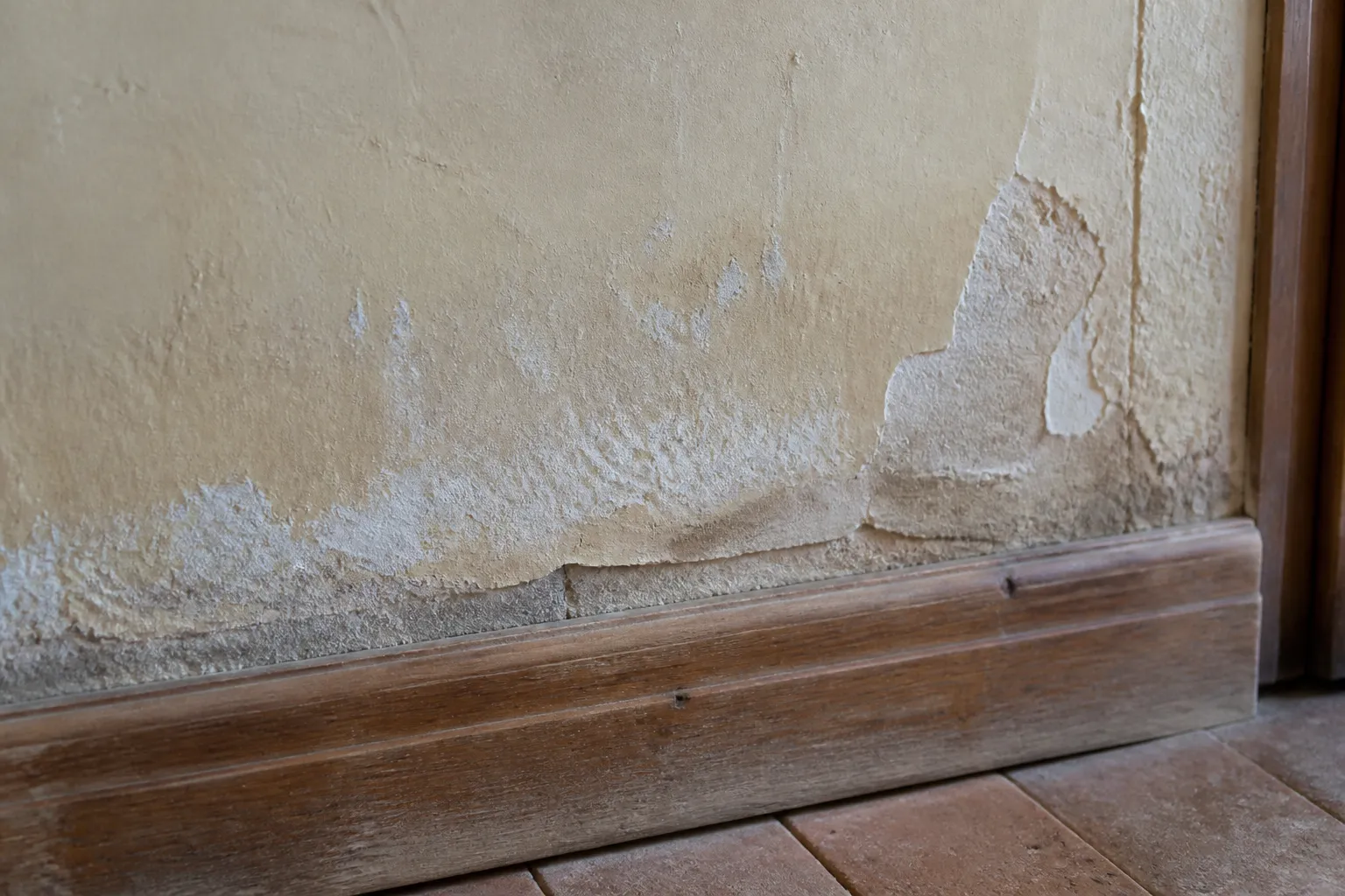 Mur intérieur en pied de façade avec enduit qui se décolle sous l’effet de l’humidité