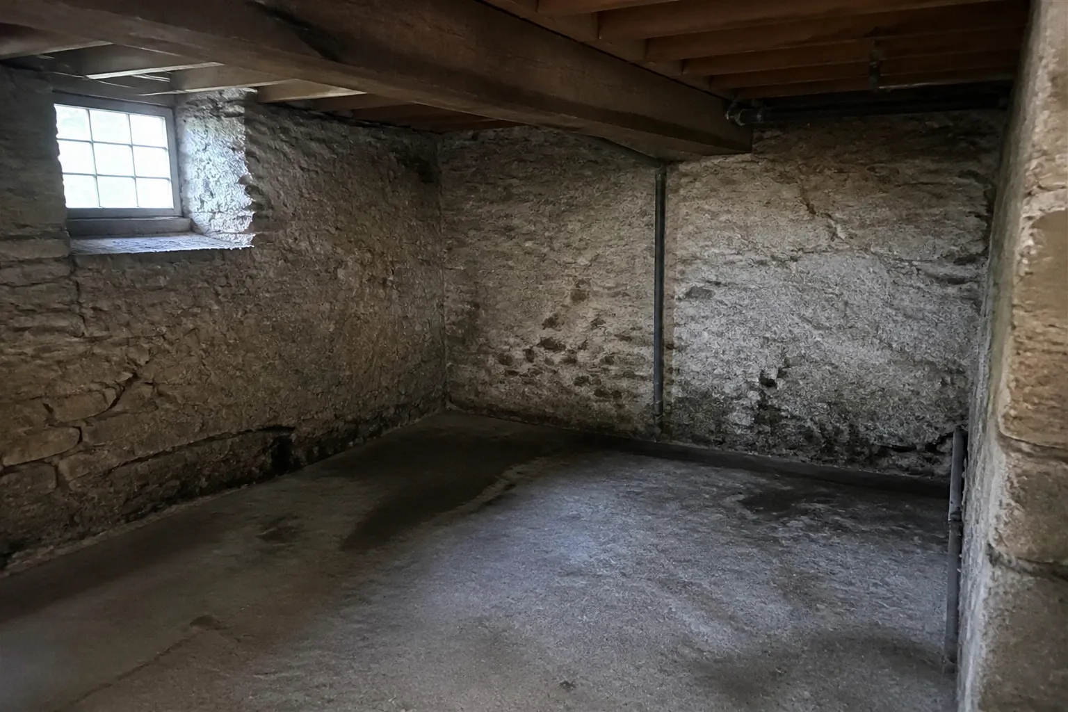 Sous-sol avec murs en pierre et traces d’humidité en partie basse