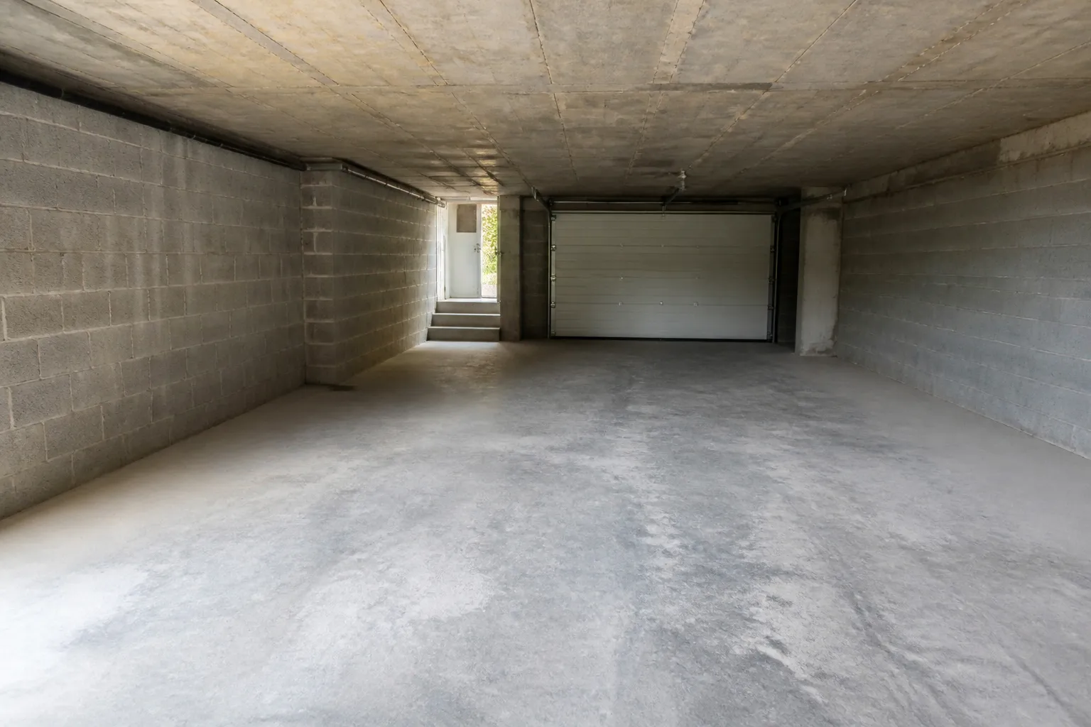 Sous-sol de pavillon avec porte de garage et dallage béton