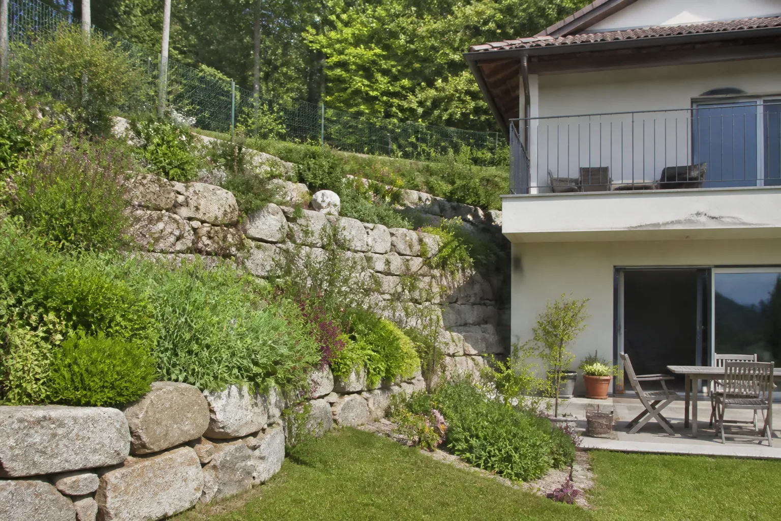Talus et mur de soutènement derrière une maison sur un terrain en pente
