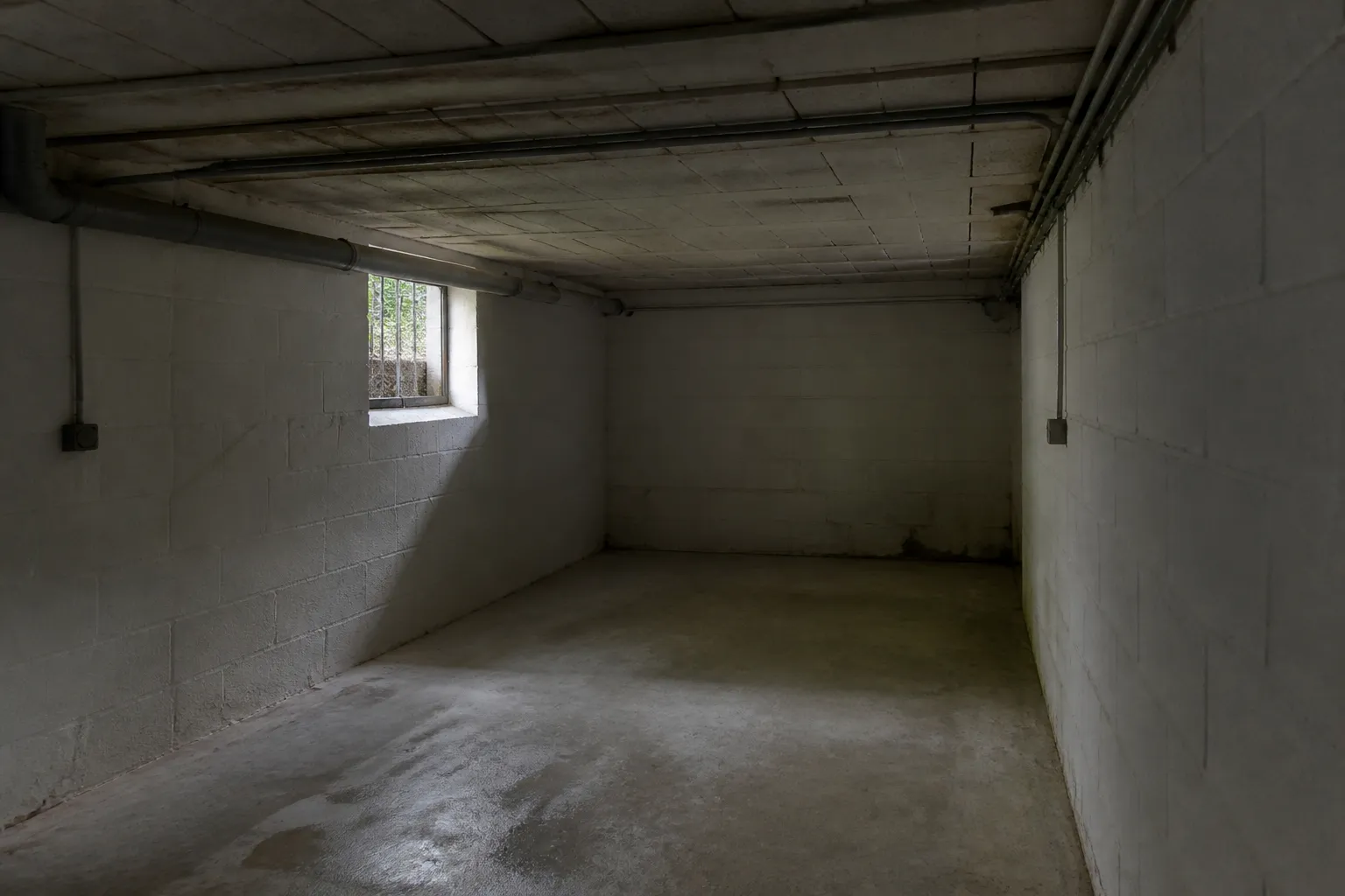 Sous-sol de maison avec murs en parpaing et soupirail
