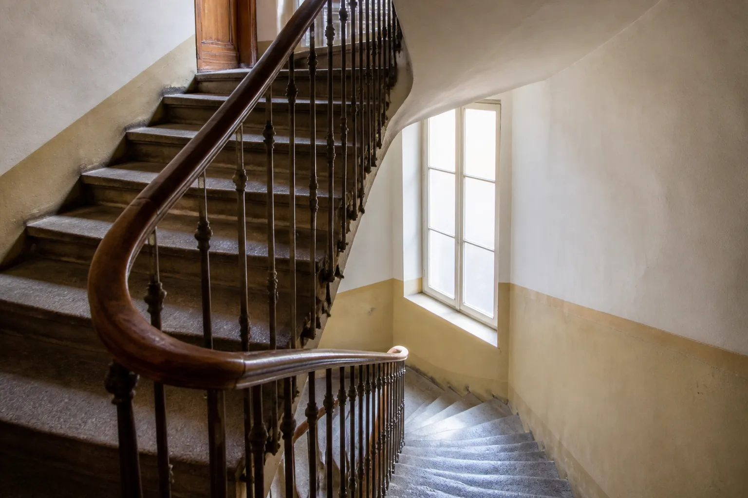 Cage d’escalier d’un immeuble ancien avec rampe en bois