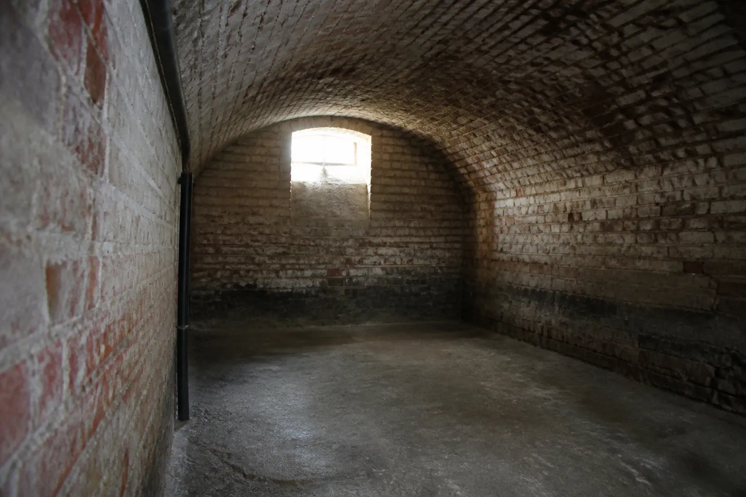 Cave voûtée en brique avec traces d’humidité au pied des murs