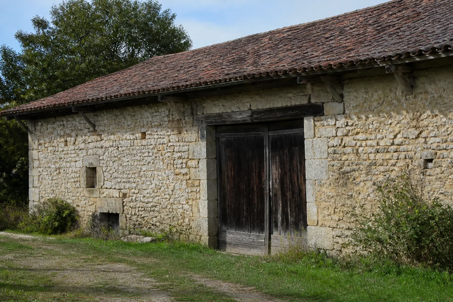Ancien bâtiment agricole en pierre avec grande porte en bois