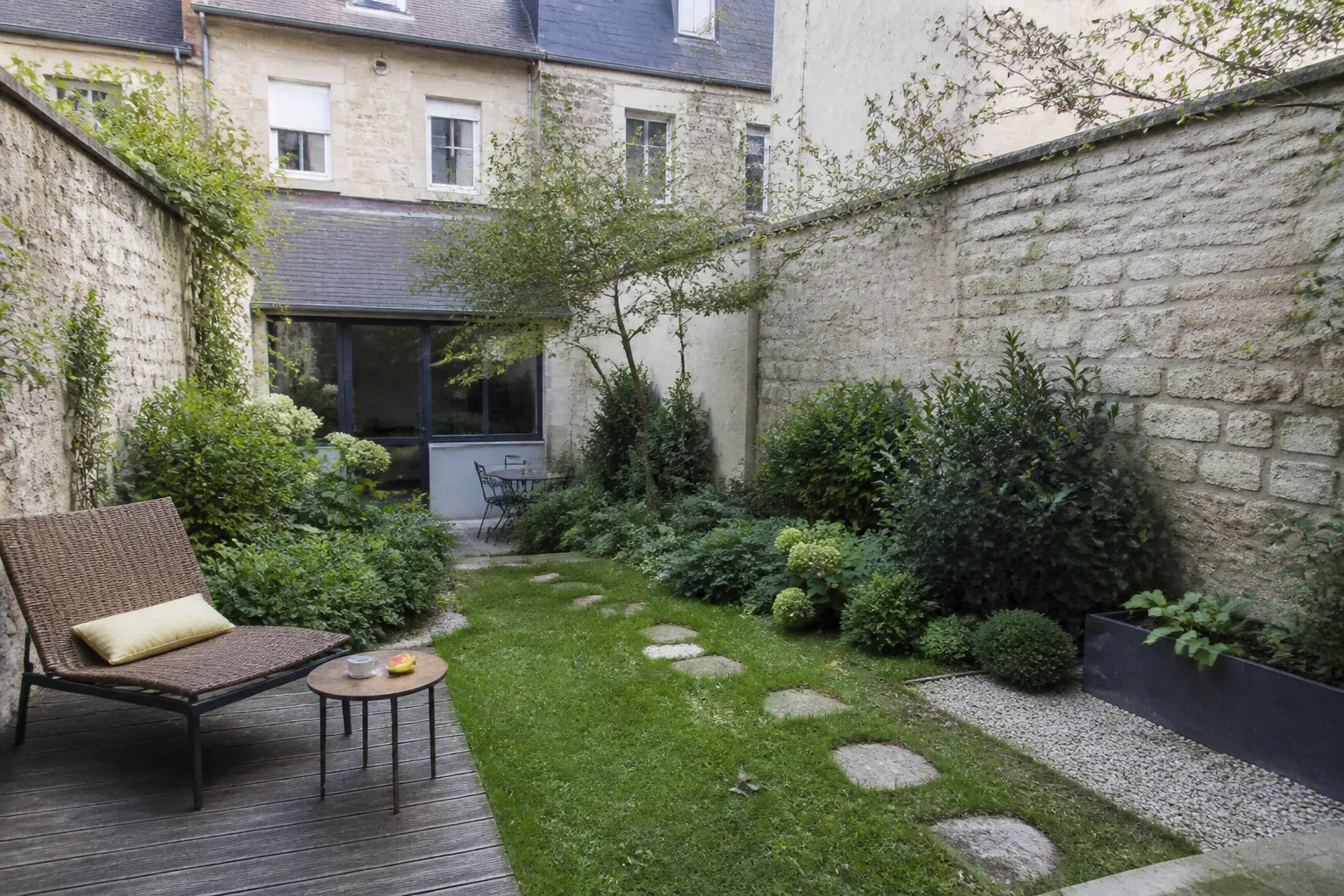 Jardin à l’arrière d’une maison de ville avec mur en pierre