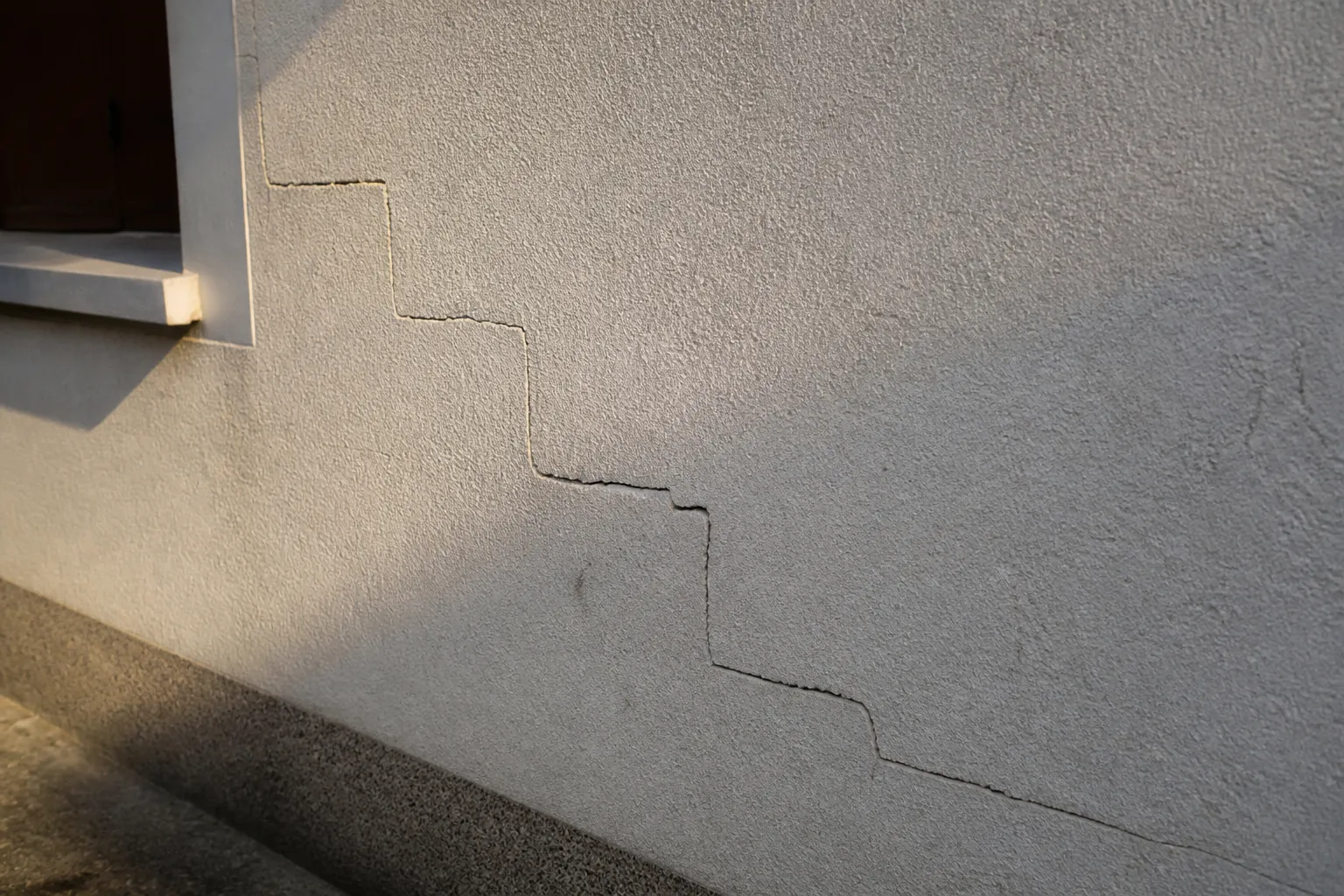 Fissure en escalier sur un mur extérieur enduit