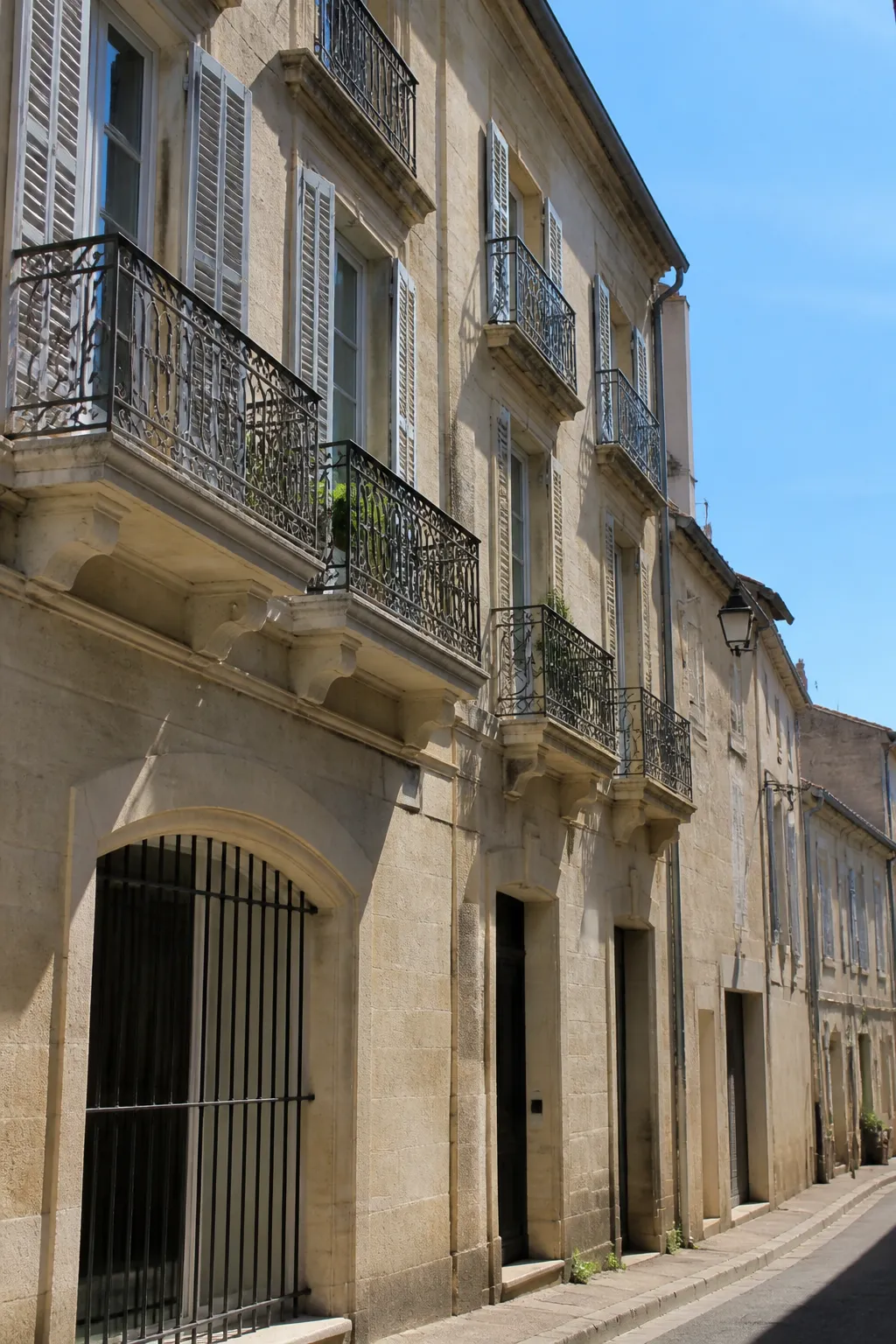 Façade d’immeuble ancien en pierre de taille claire avec balcons en fer forgé