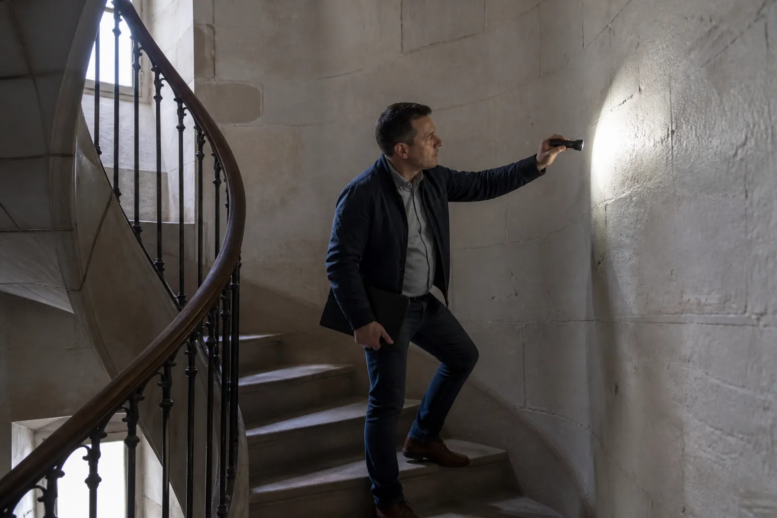 Expert inspectant une cage d’escalier d’immeuble avec une lampe