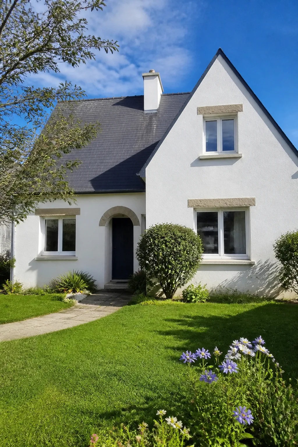 Maison individuelle avec jardin et toiture en ardoise dans un quartier résidentiel