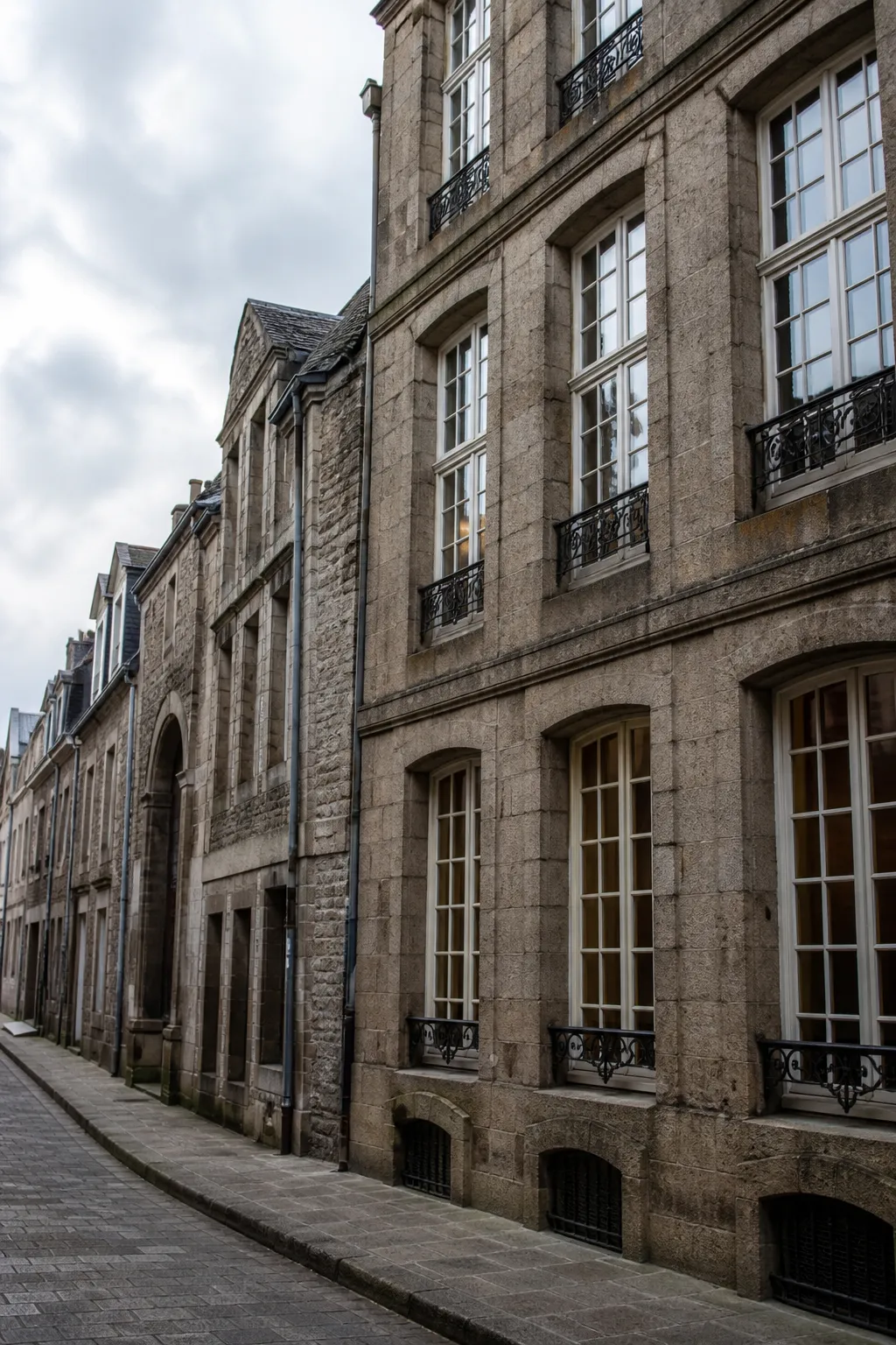 Immeuble ancien en pierre avec fenêtres hautes dans une rue de centre-ville