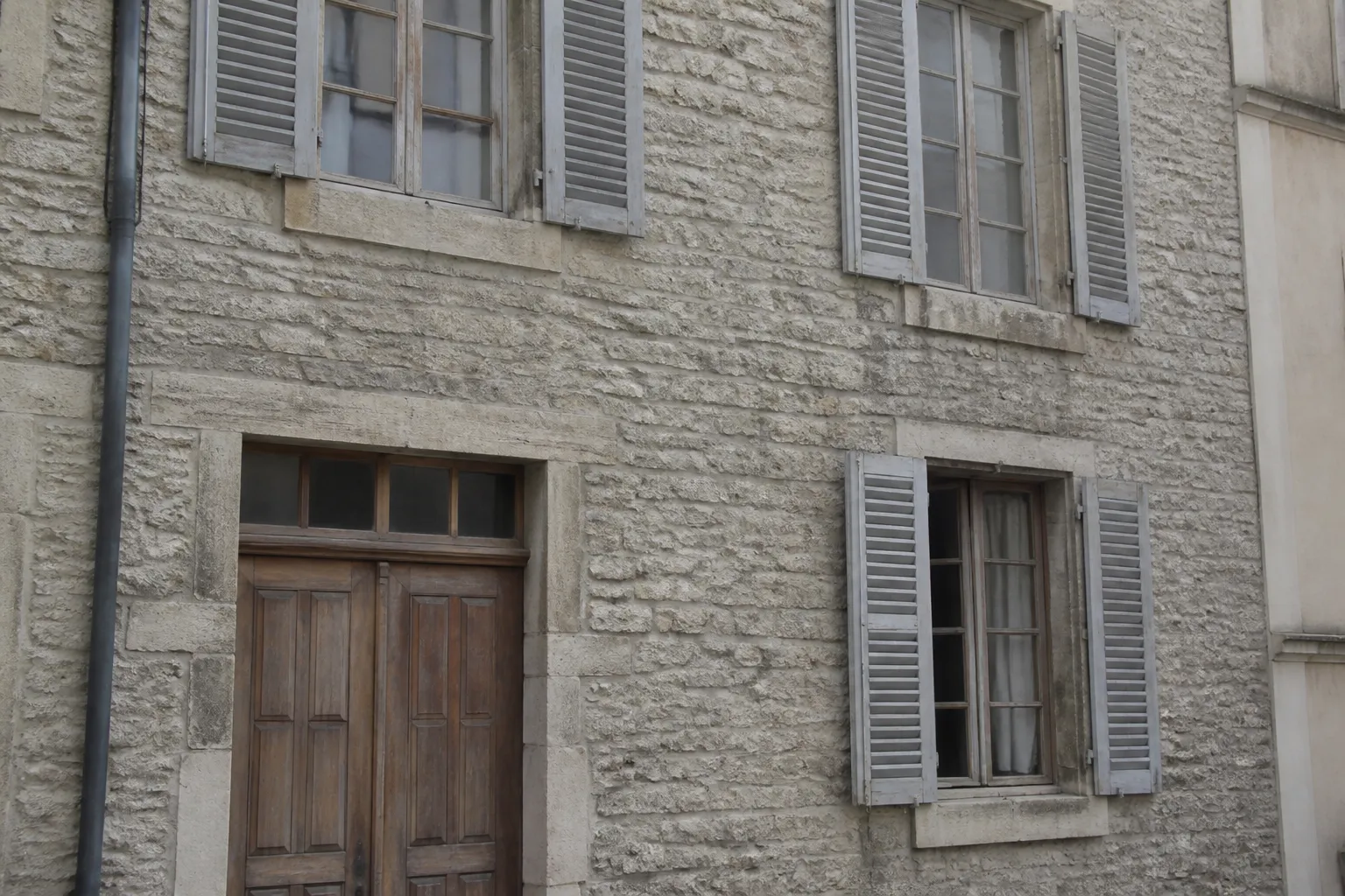 Façade en pierre et menuiseries en bois d’une maison de ville ancienne