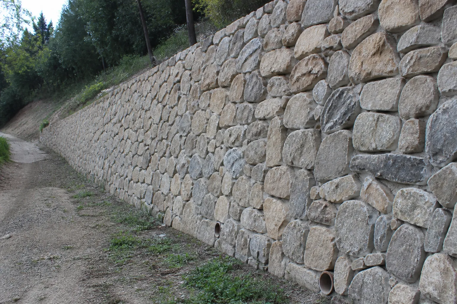 Mur de soutènement en pierre avec barbacanes au bord d’un terrain en pente