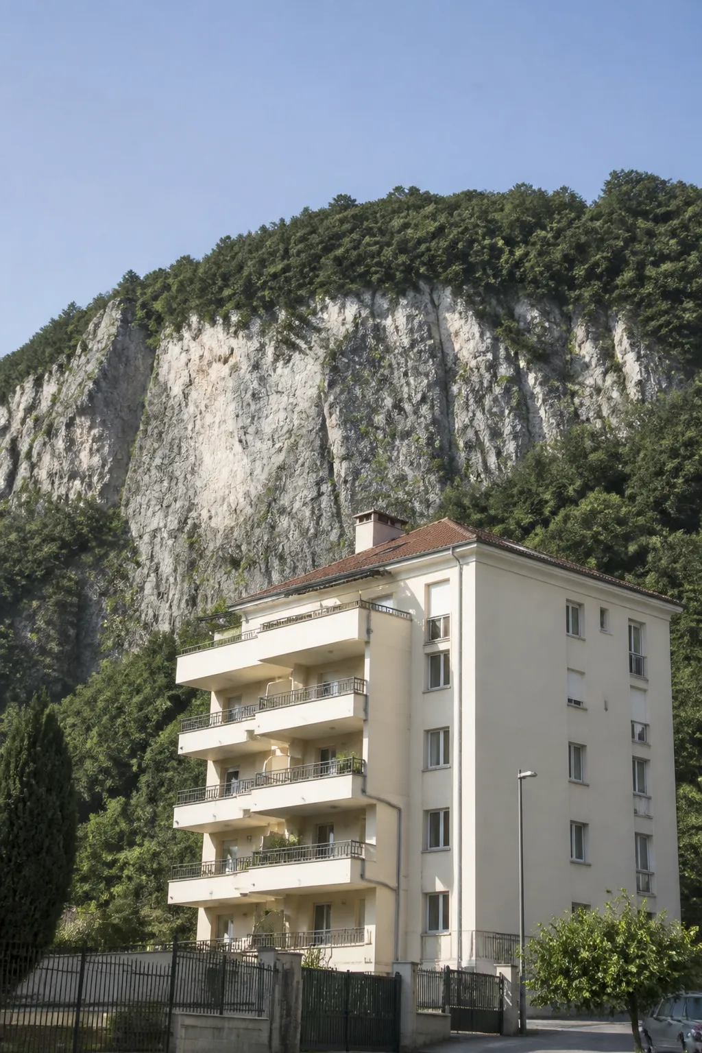 Petit immeuble résidentiel au pied d’une falaise boisée