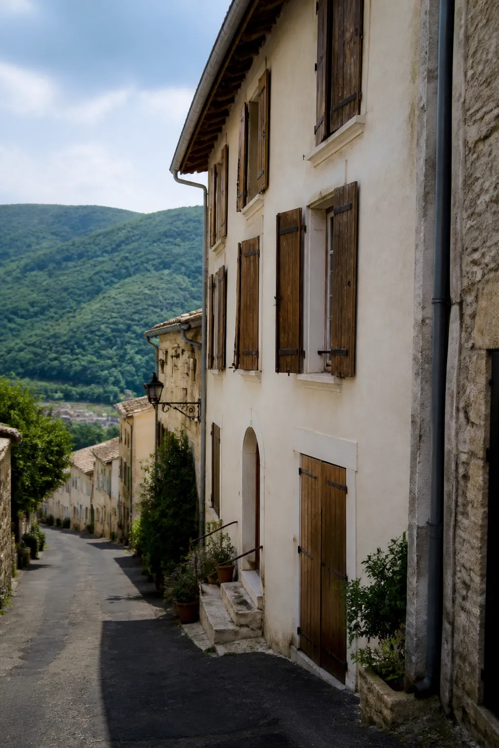 Maison de ville ancienne aux volets en bois sur une rue en pente