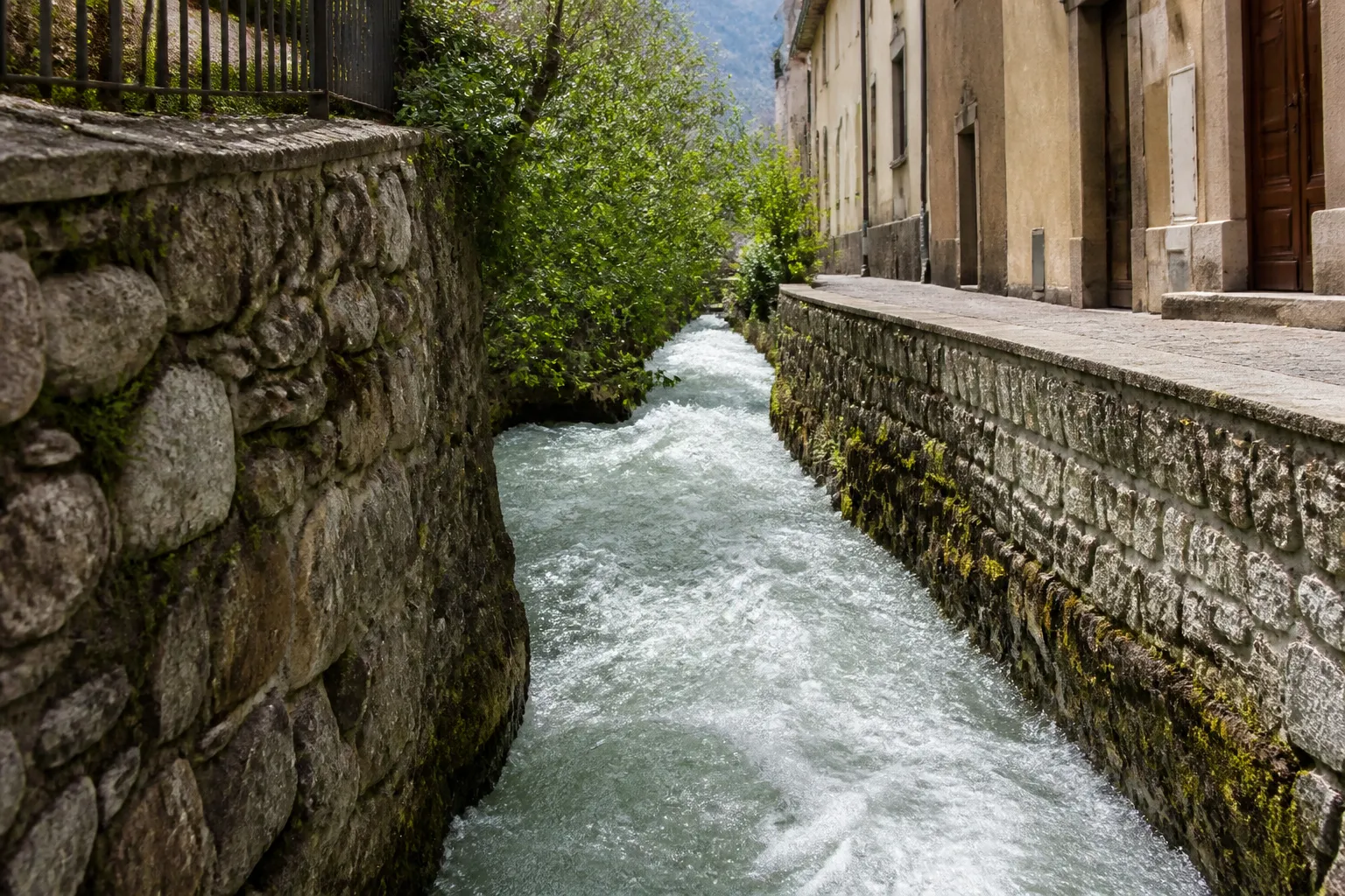Torrent étroit canalisé entre des murs de pierre en ville