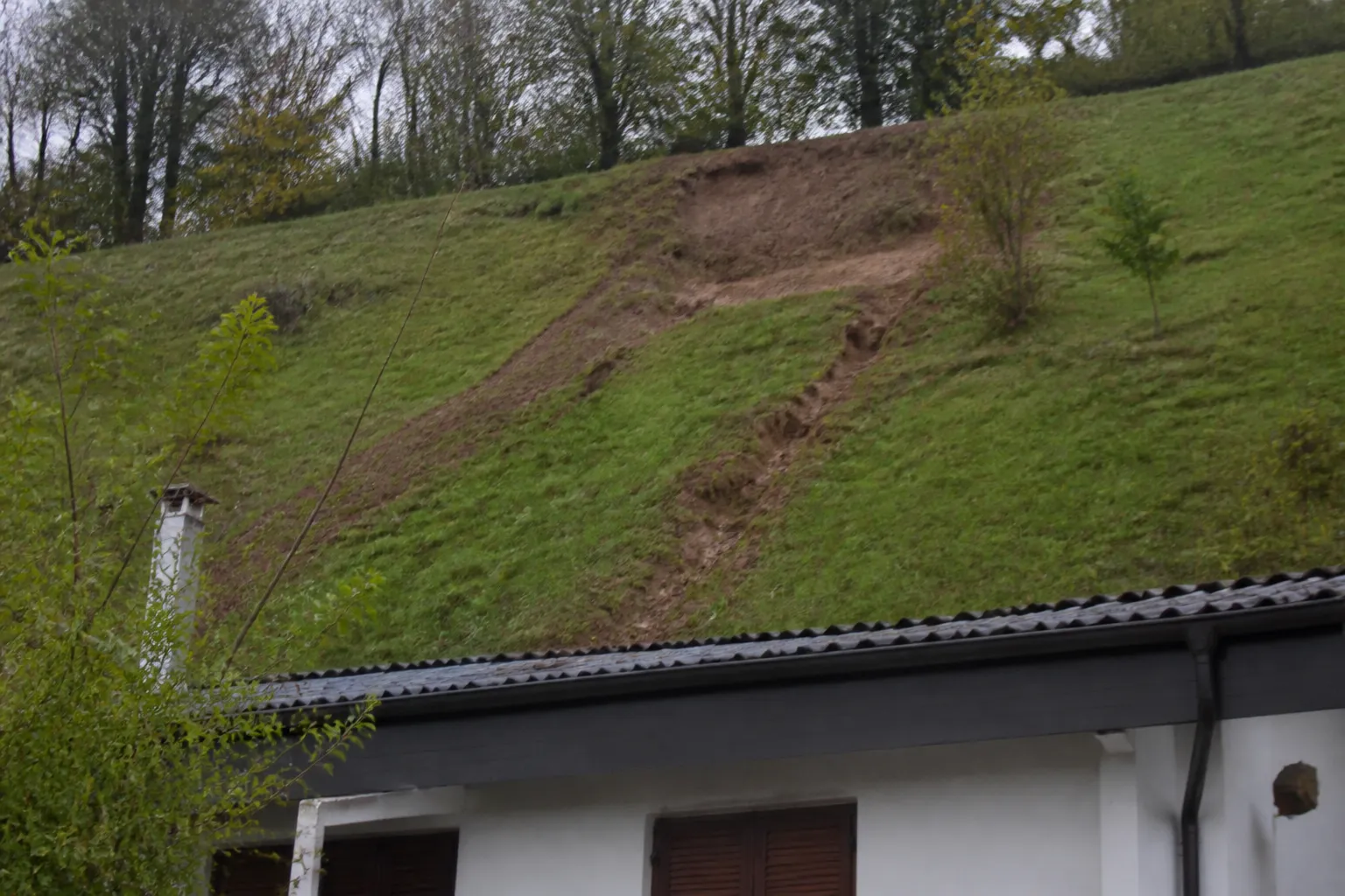 Ravinement sur un talus herbeux au-dessus d’une maison