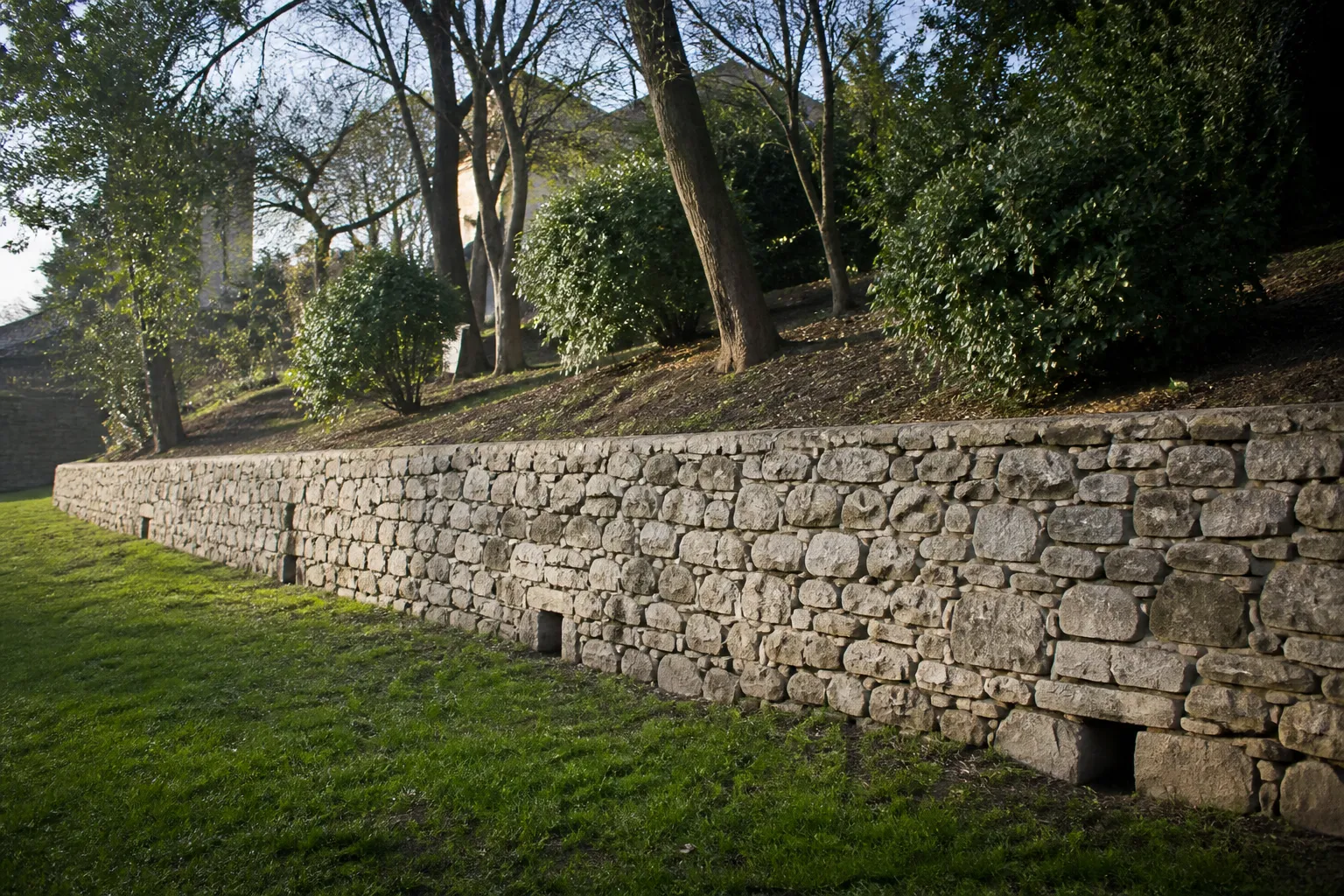 Mur de soutènement en pierre au bas d’un jardin en pente