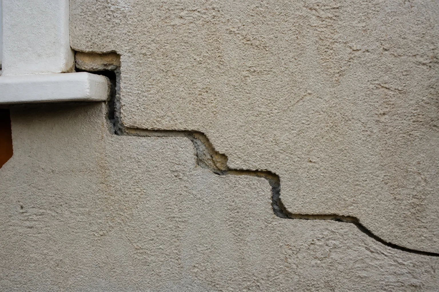 Fissure en escalier sur un mur extérieur enduit