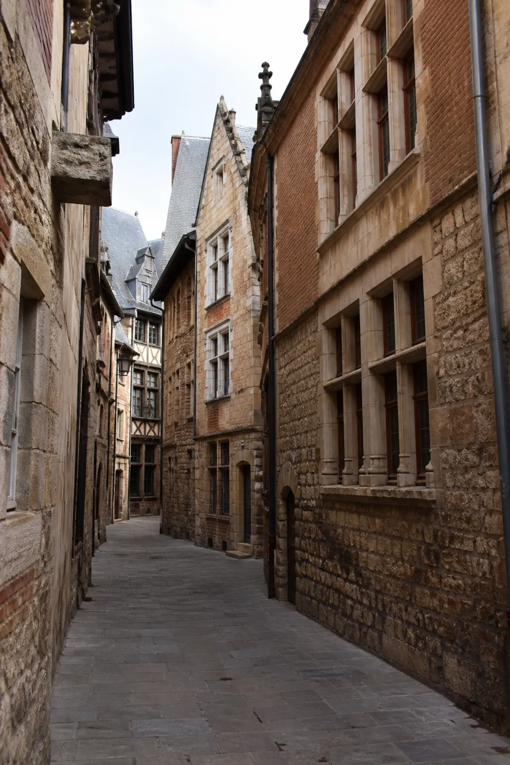 Façades anciennes en pierre et brique dans une rue étroite de centre historique
