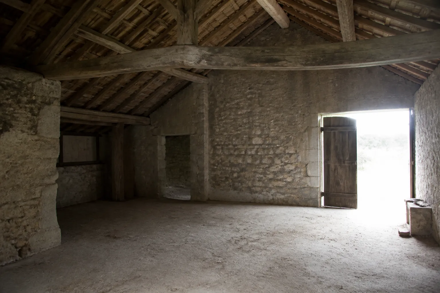 Intérieur d’une grange en pierre avec charpente en bois