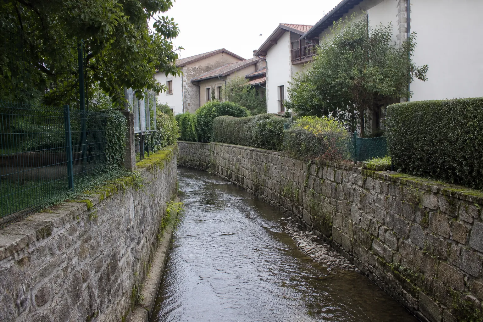 Petit ruisseau canalisé en ville bordé de maisons