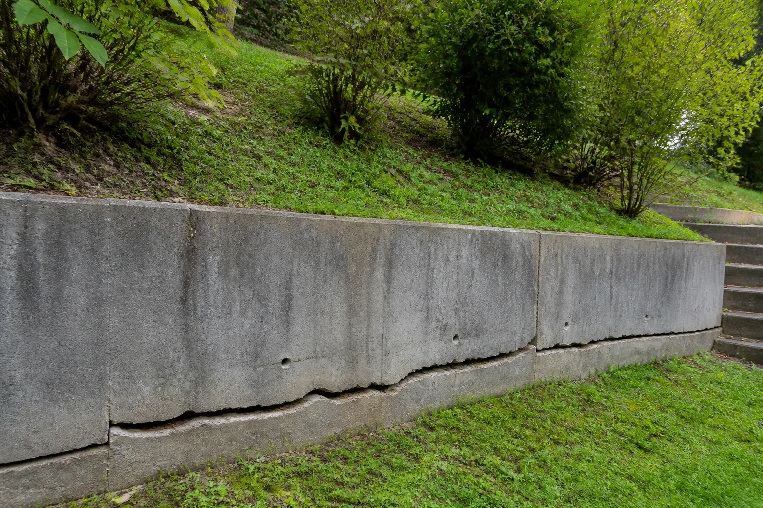 Mur de soutènement fissuré au bas d’un jardin en pente