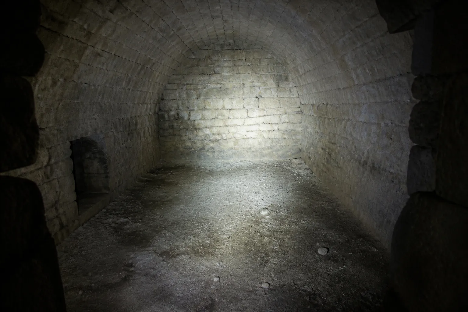 Cave voûtée en pierre éclairée par une lampe