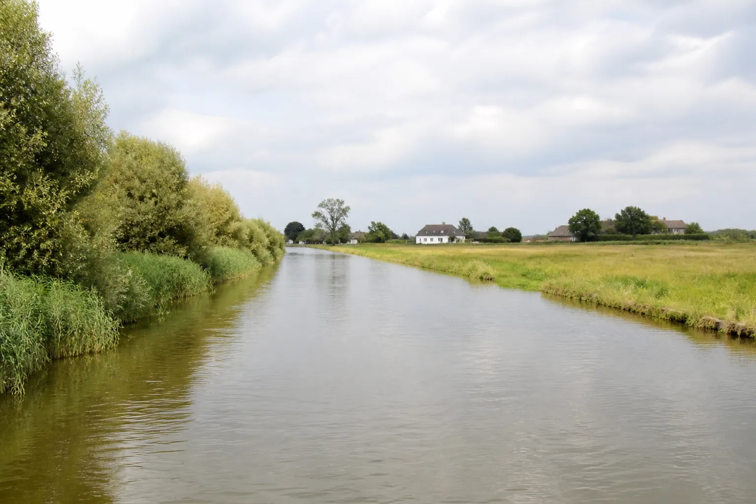 Canal bordé de prairies humides près d’une petite ville