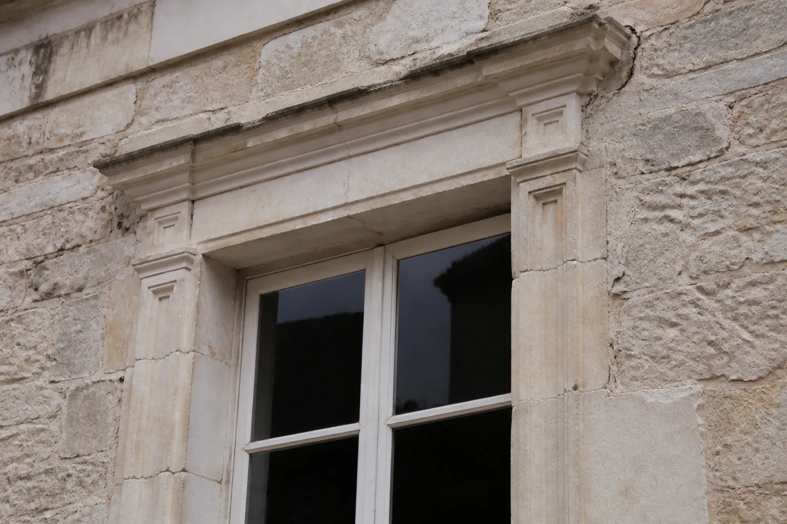 Détail d’une façade en pierre avec encadrement de fenêtre sculpté